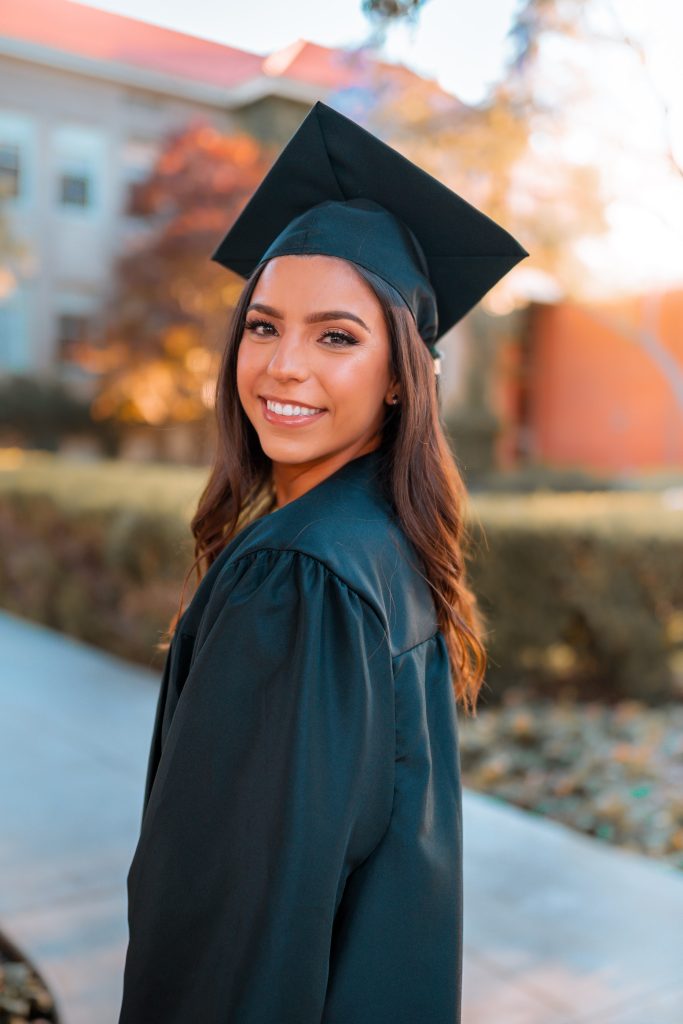 A girl in her cap and gown smiling.